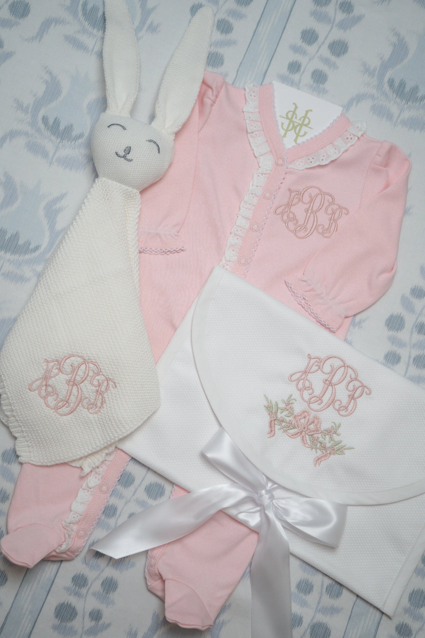 Personalized baby gift bundle with coordinating pieces and embroidered monogram; styled view