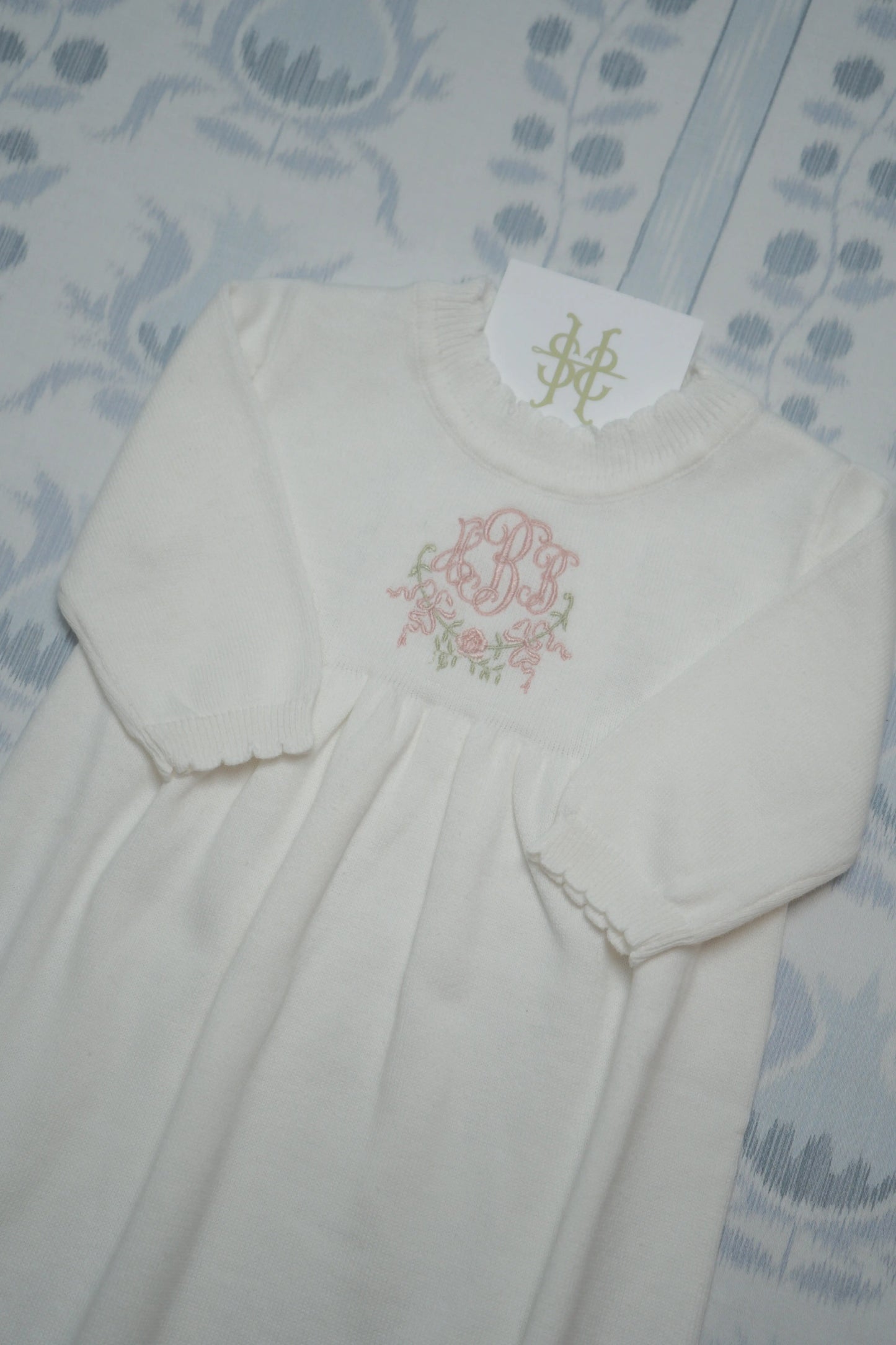 Personalized scalloped knit gown and keepsake bag bundle with custom embroidery for a newborn outfit; styled view