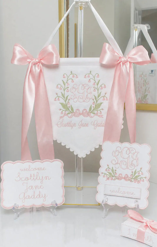 Personalized Bell Flower Baby Banner displayed with matching bassinet plaque and baby milestone card