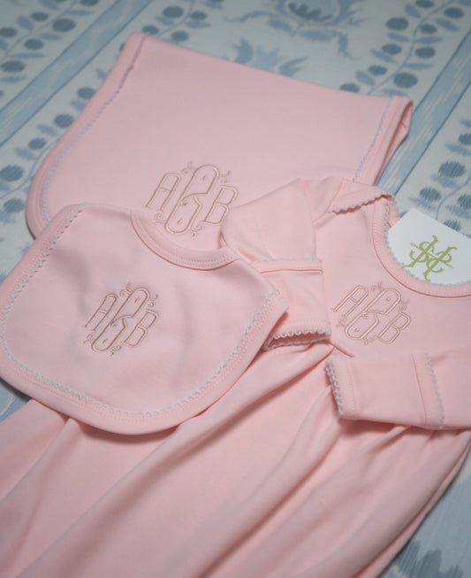 Personalized picot trim gown, bib, and burp cloth bundle with custom embroidery for a newborn outfit; styled view