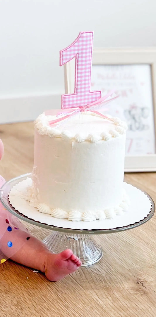 Personalized cake topper with embroidery for a first birthday or milestone celebration; styled view
