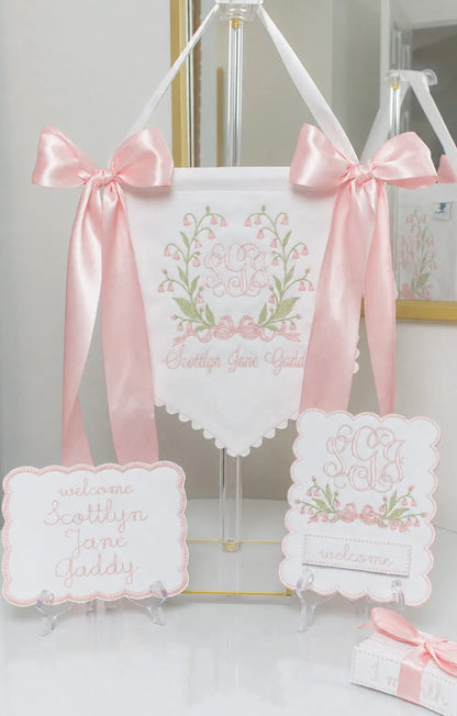 Personalized Bell Flower Baby Banner displayed with matching bassinet plaque and baby milestone card